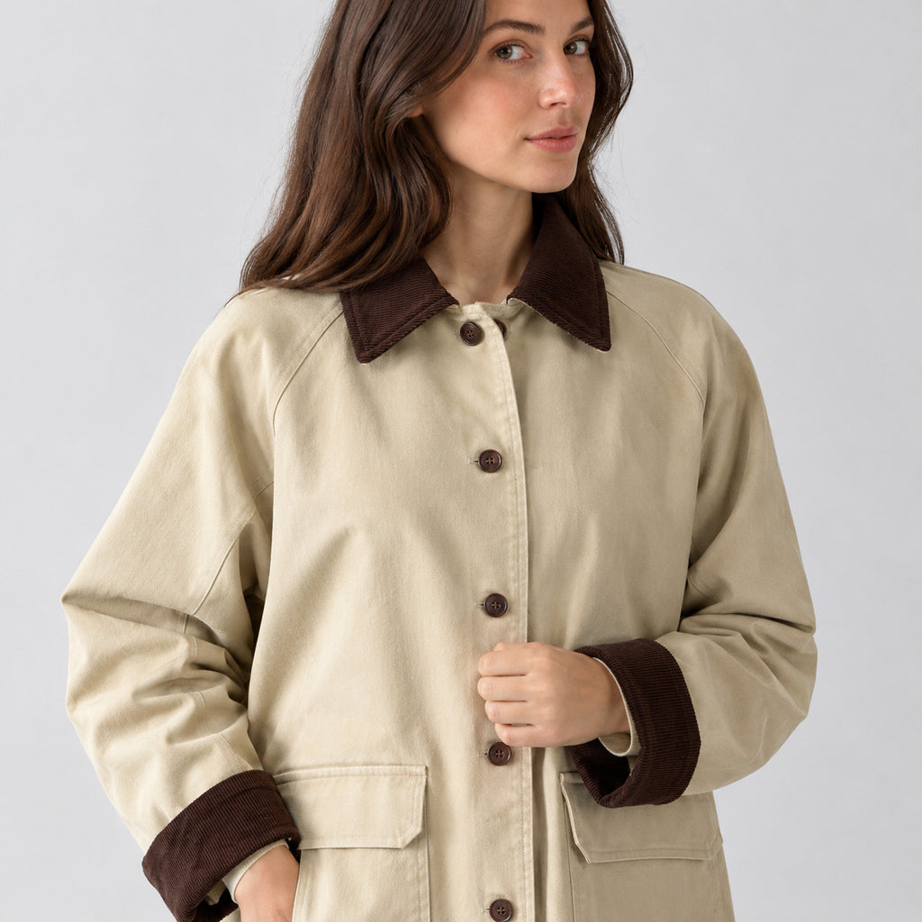 Light beige barn jacket worn, cropped from the shoulders to the waist to show the corduroy collar and button placket.
