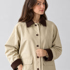 Light beige barn jacket worn, cropped from the shoulders to the waist to show the corduroy collar and button placket.