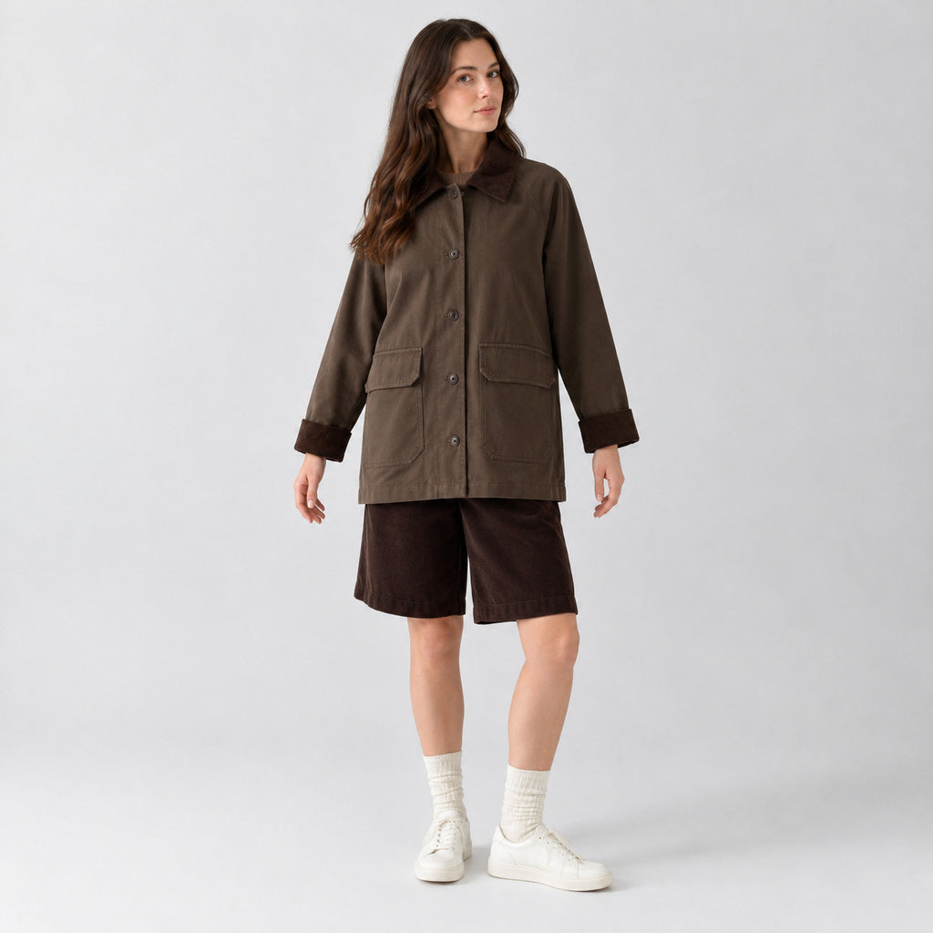 Dark brown barn jacket with corduroy collar worn by a model in a neutral studio.