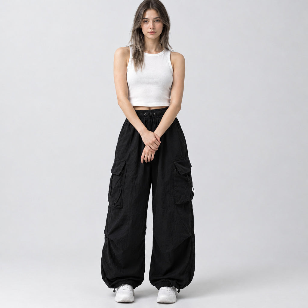 Black wide-leg parachute cargo pants worn by a model in a neutral studio setting.