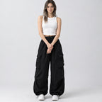 Black wide-leg parachute cargo pants worn by a model in a neutral studio setting.