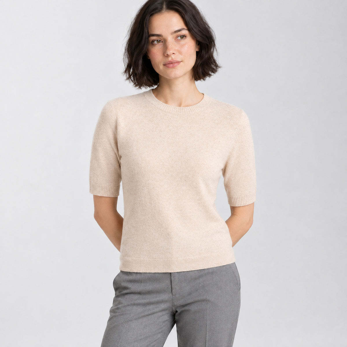 Light beige crewneck half-sleeve sweater worn by a model in a neutral studio.