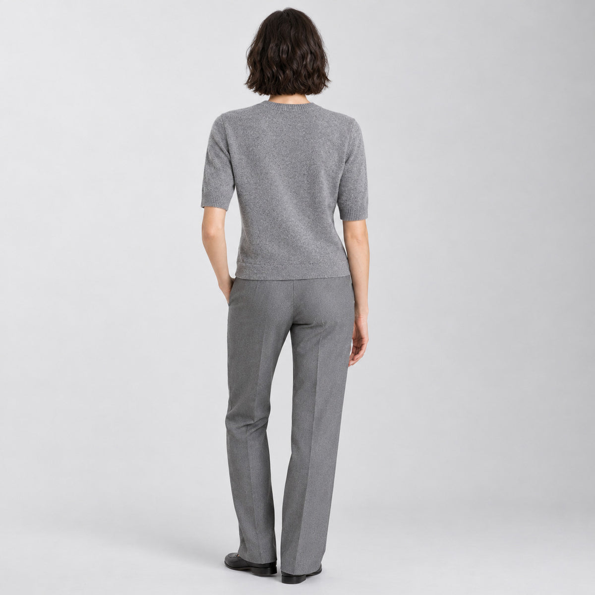 Back of the heather gray crewneck sweater worn, showing the plain knit back.