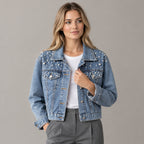 Light blue pearl-embellished denim jacket worn by a model in a neutral studio.