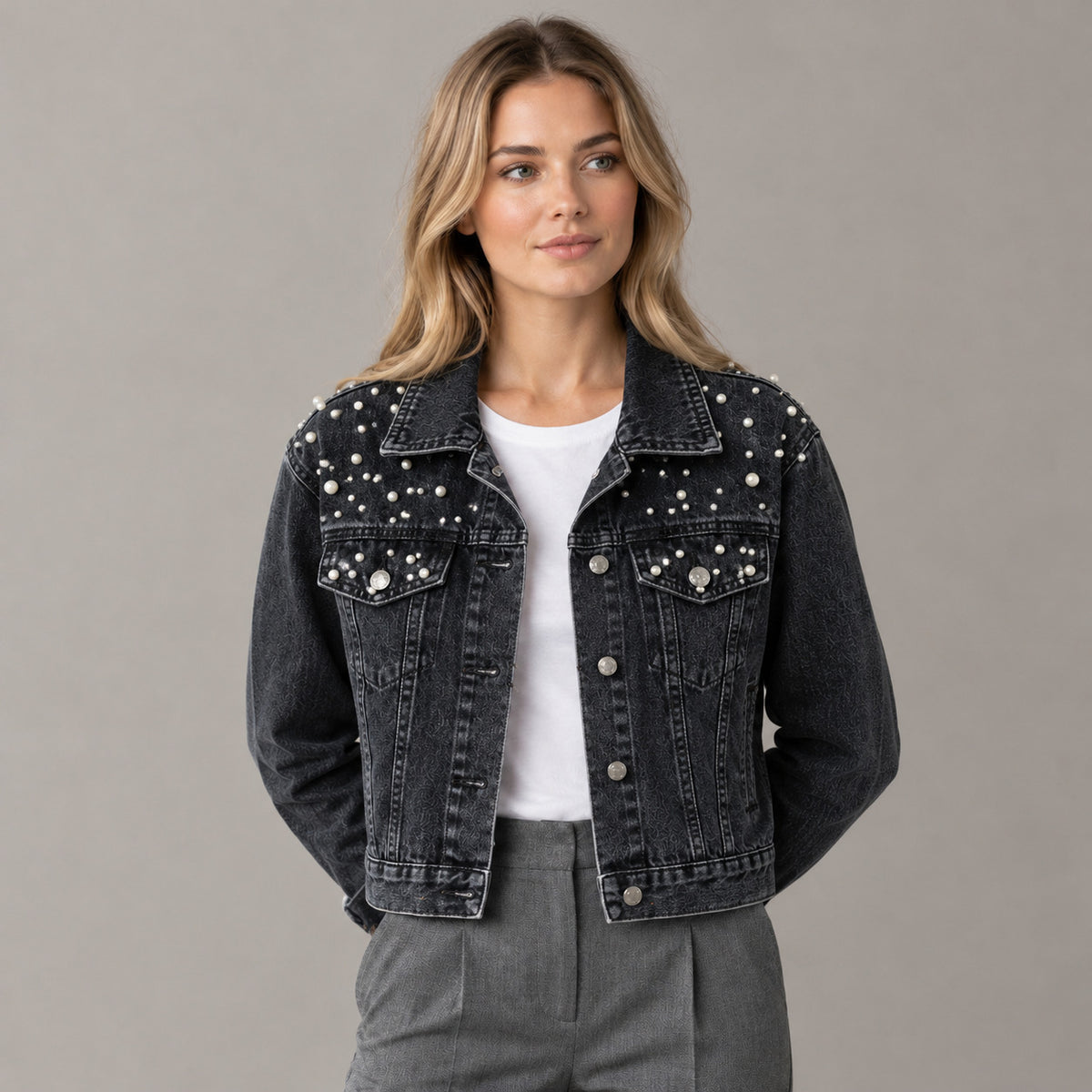 Black pearl-embellished denim jacket worn by a model in a neutral studio.