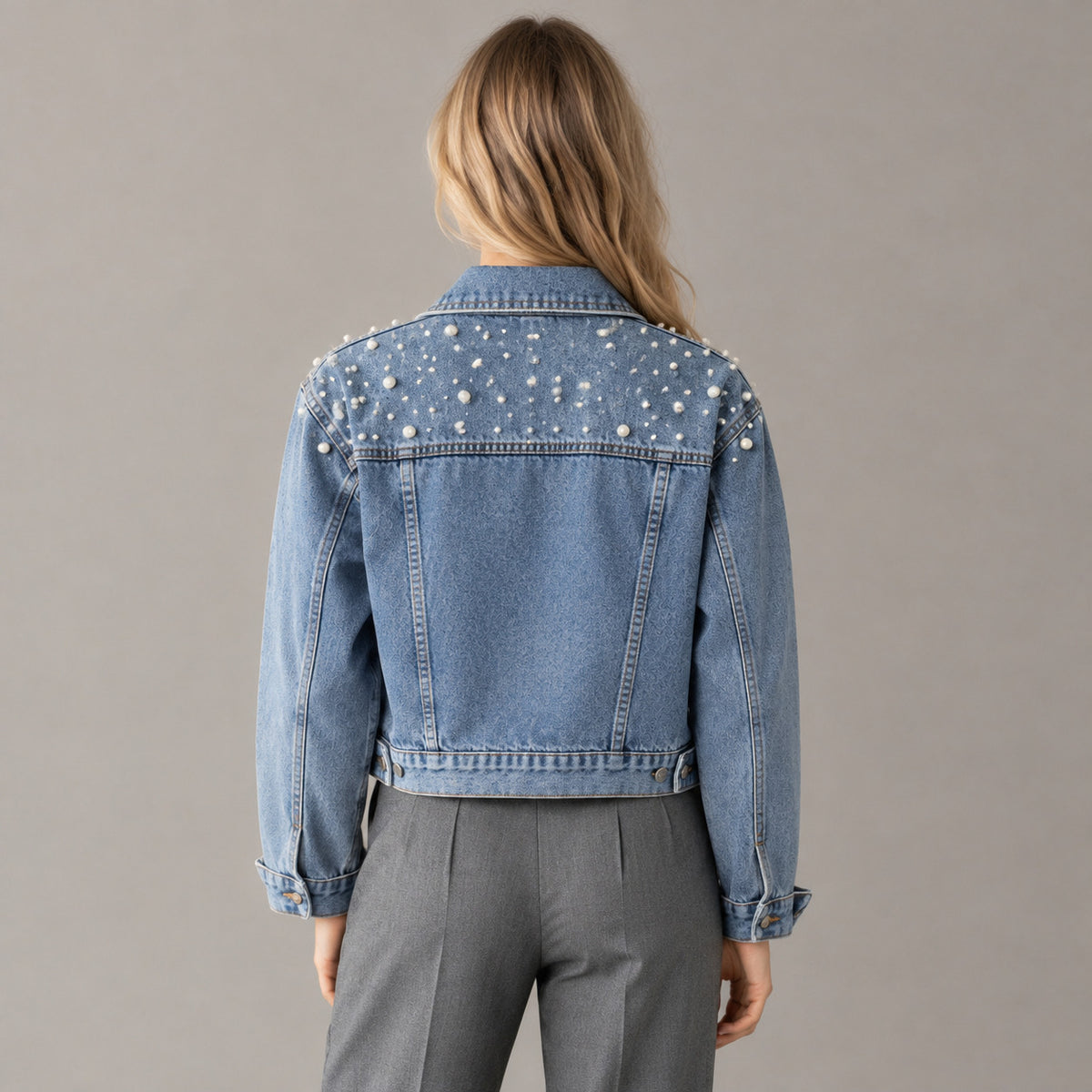 Back of the light blue pearl-embellished denim jacket worn, showing the pearl-studded back yoke.