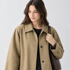 Khaki relaxed single-breasted trench coat worn, cropped from the shoulders to the waist to show the fold-down collar and button placket.