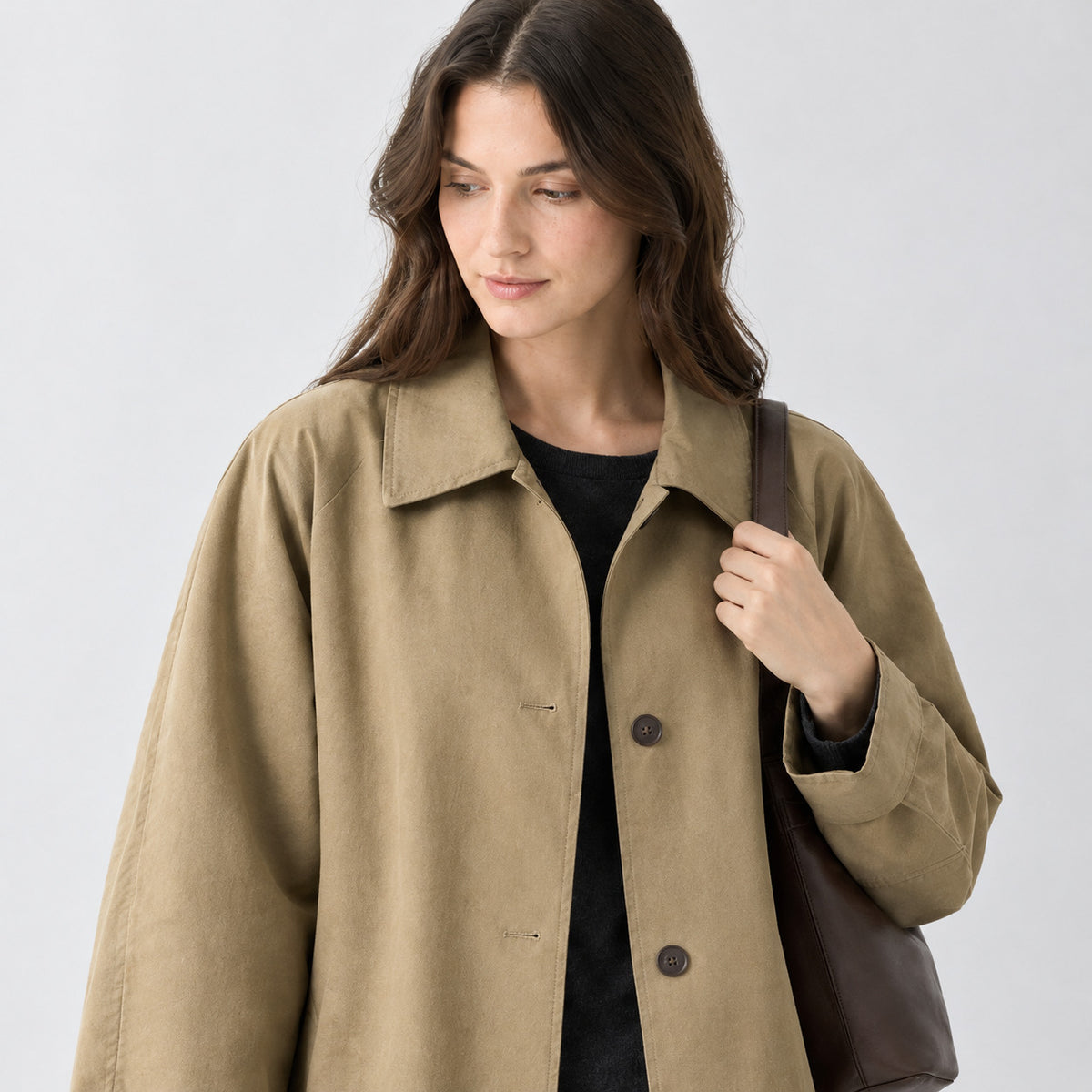 Khaki relaxed single-breasted trench coat worn, cropped from the shoulders to the waist to show the fold-down collar and button placket.