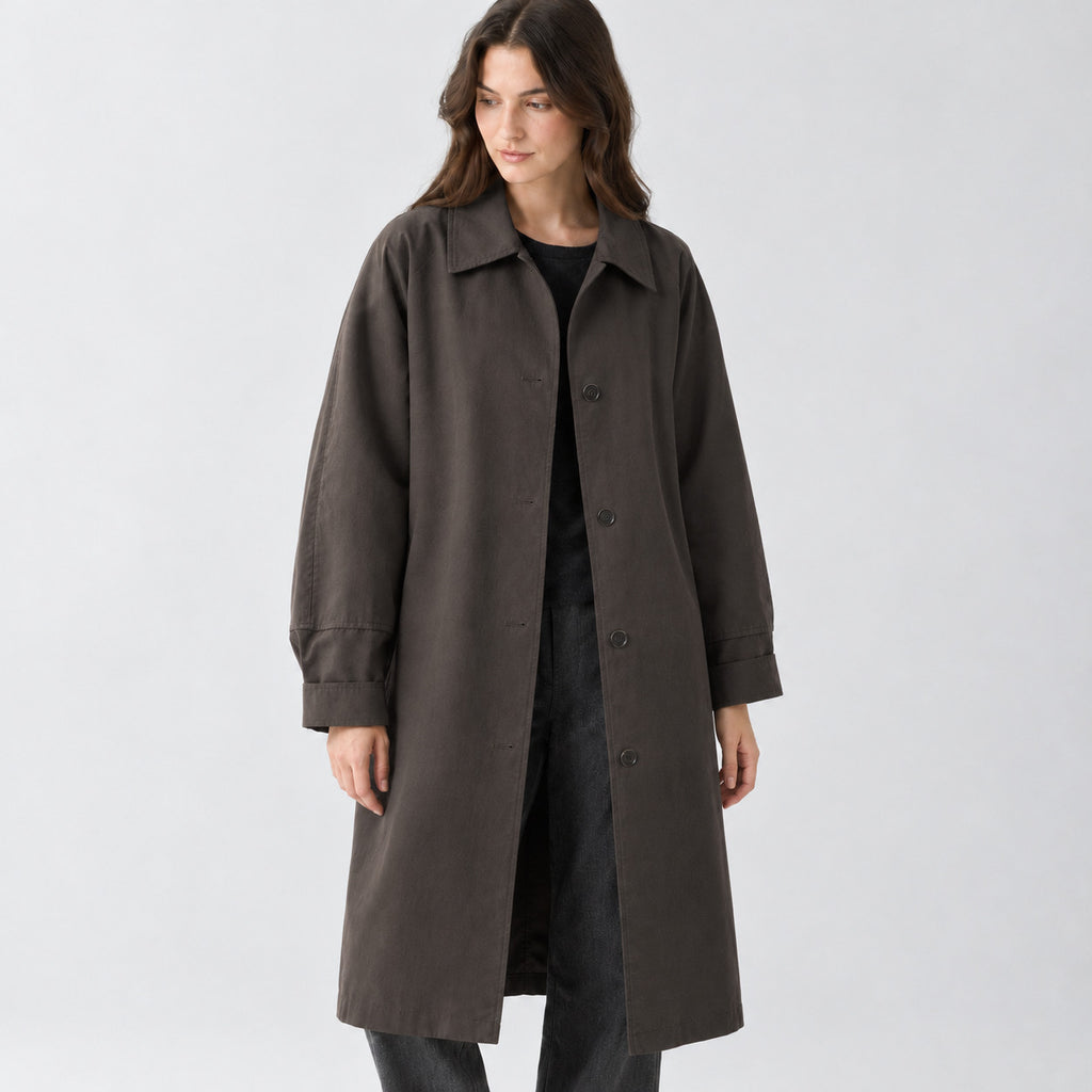 Dark brown relaxed single-breasted trench coat worn by a model in a studio setting.