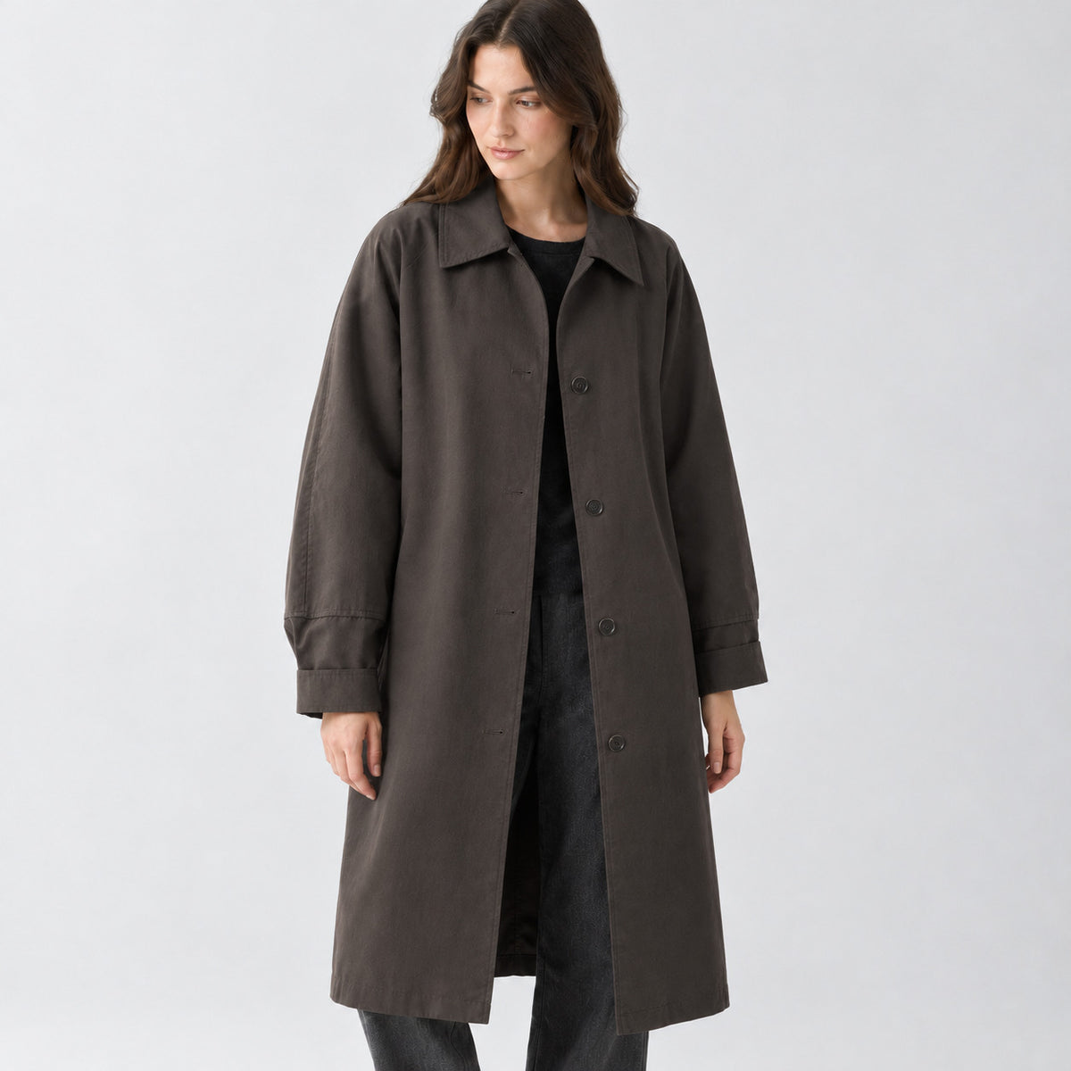 Dark brown relaxed single-breasted trench coat worn by a model in a studio setting.