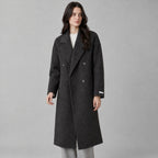 Charcoal gray double-breasted long wool coat worn by a model against a neutral studio backdrop.