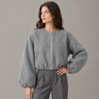 Gray cropped collarless zip-up jacket worn by a model in a neutral studio.