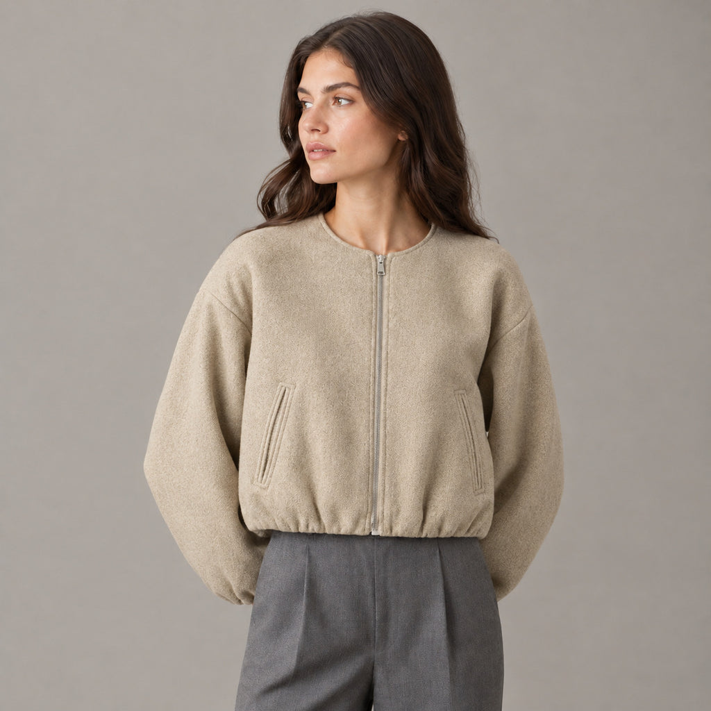 Khaki cropped collarless zip-up jacket worn by a model in a neutral studio.