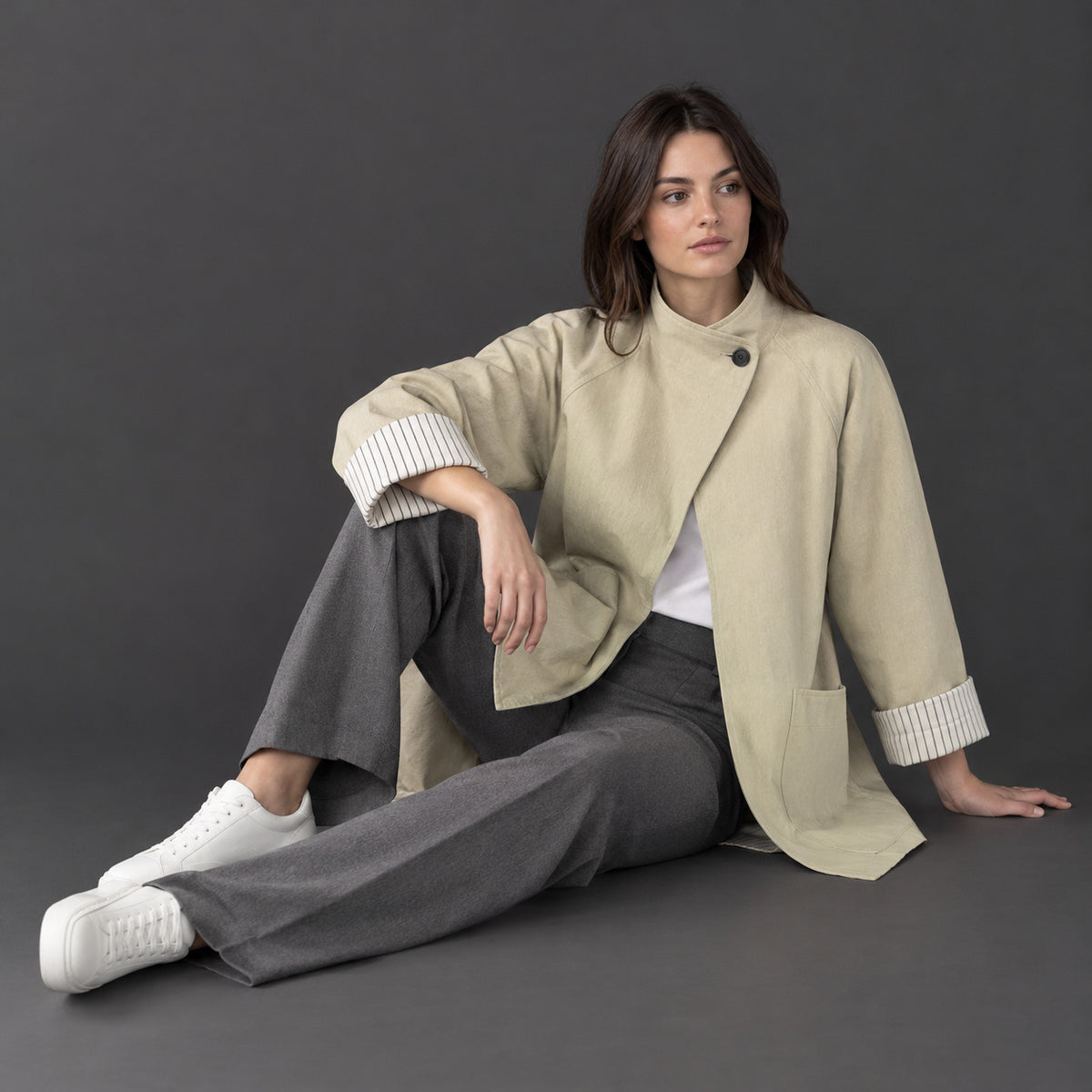Off-white relaxed stand-collar trench coat worn by a model against a neutral studio backdrop.