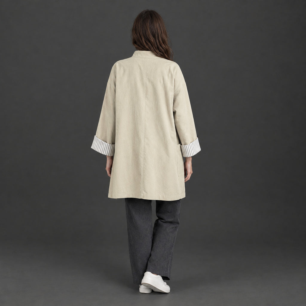 Back of the off-white relaxed stand-collar trench coat worn, showing the centre back seam.