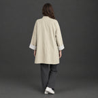 Back of the off-white relaxed stand-collar trench coat worn, showing the centre back seam.